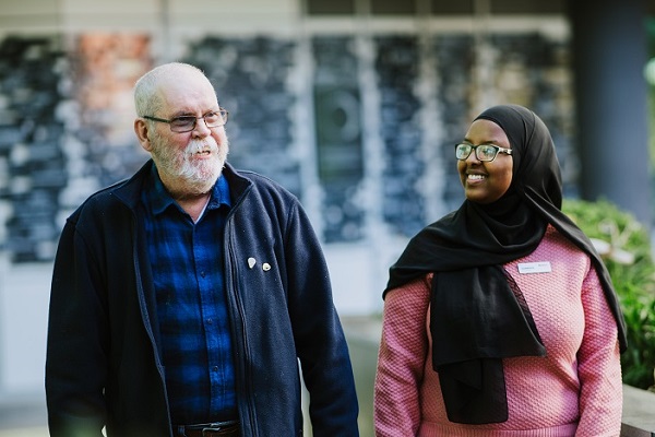 Volunteer walking and smiling with a patient